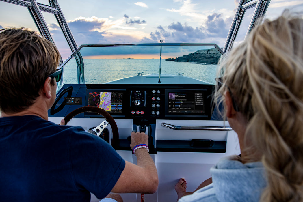 Two people on a boat at sunset with a scenic view. GPSMAP 923