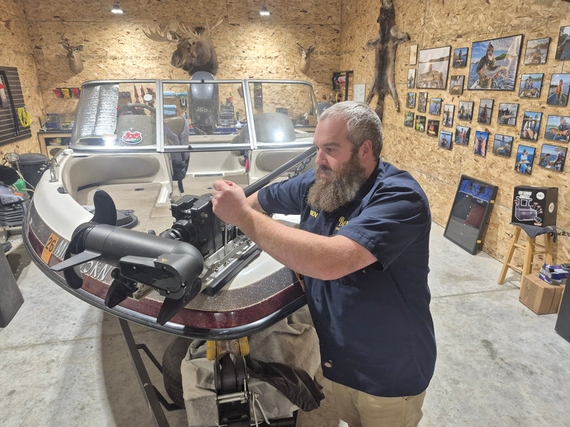 Close-up of technician tightening bolts on trolling motor bracket during installation